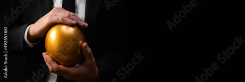 Fotografi Golden egg in hands of elegant businessman as symbol of guaranteed success, profit or wealth