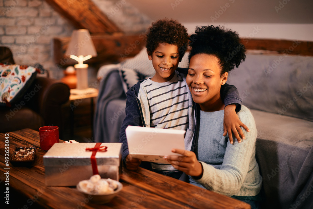 Happy black mother receives gift and greeting card from her son on Mother's day. Happy black mother receives gift and greeting card from her son on Mother's day.