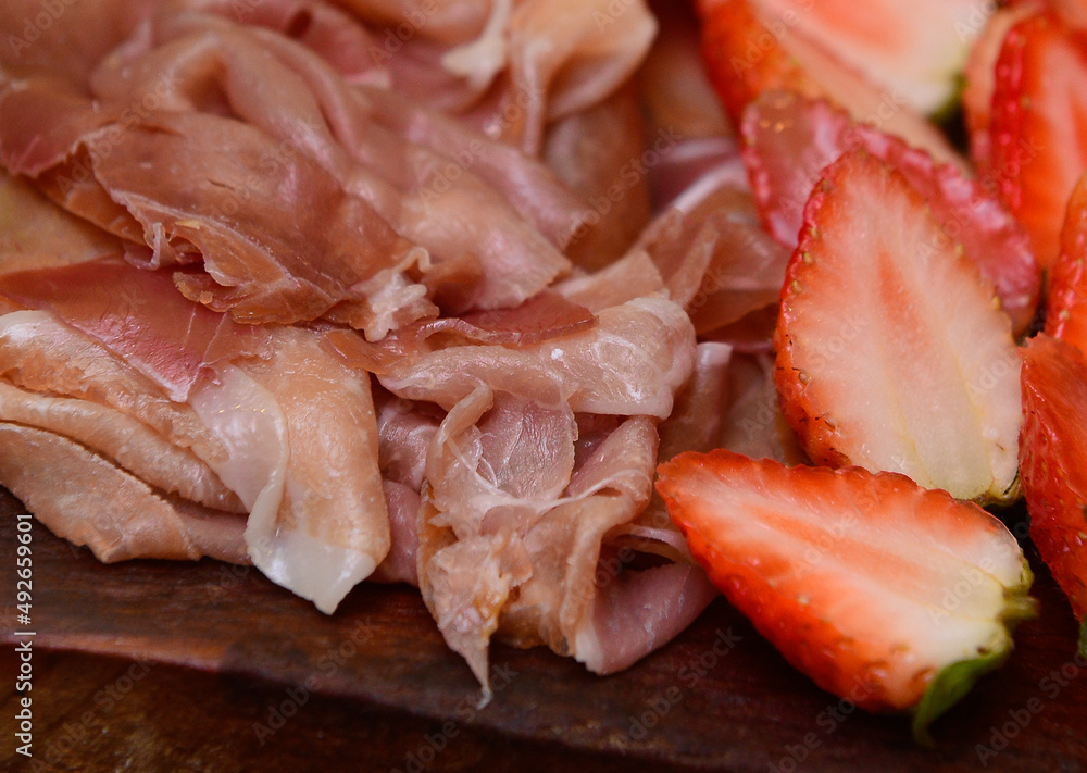 close-up of slices of ham and strawberries, cold dish, cold platter,accompaniment to wine, snack to wine close-up of slices of ham and strawberries, cold dish, cold platter,accompaniment to wine, snack to wine