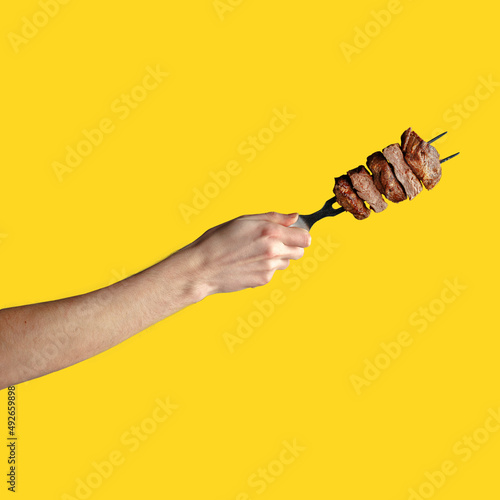 a man's hand holds pieces of roasted meat on a fork