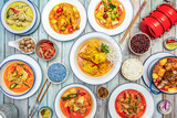 Set of cute Thai food dishes with spicy curry, stewed chicken, colored rice, pork stew, spices, chopsticks, lime and chili peppers