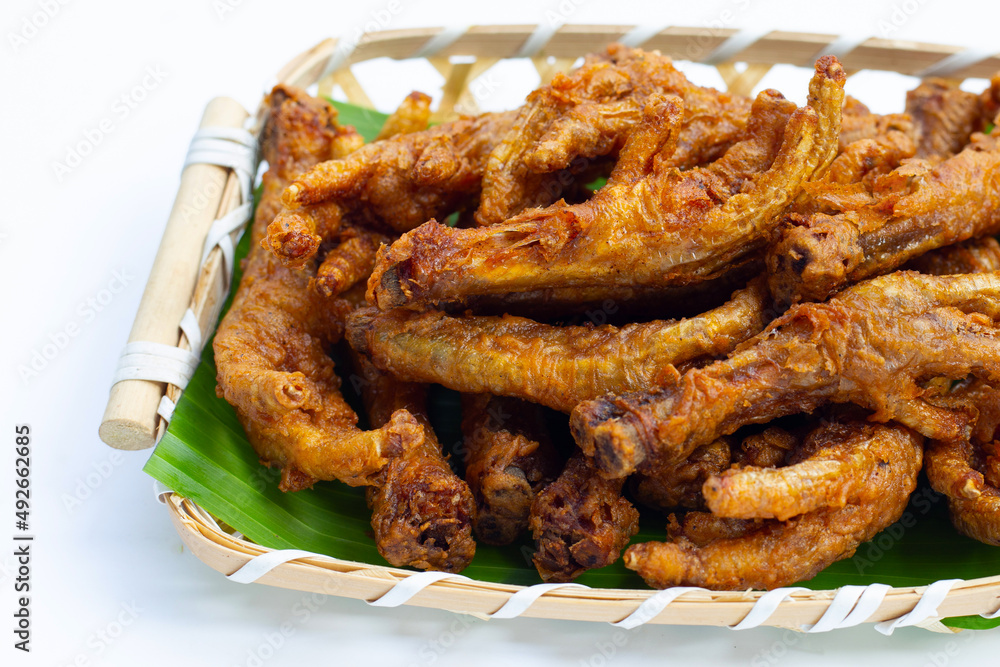 Fried chicken feet in bamboo basket on white background.
