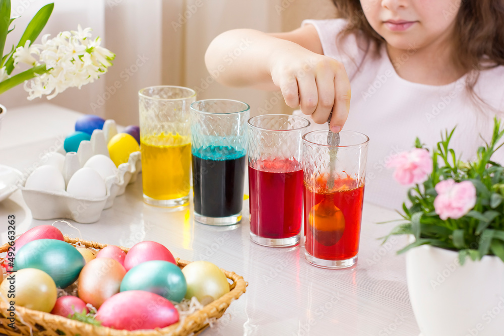 Cute little girl painting Easter eggs in glasses with liquid dye. Cute little girl painting Easter eggs in glasses with liquid dye.