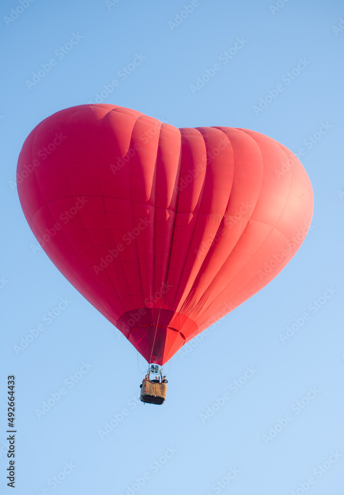Obraz premium hot air balloon floating in the sky big red hot air balloon in the shape of a big heart for love and world peace