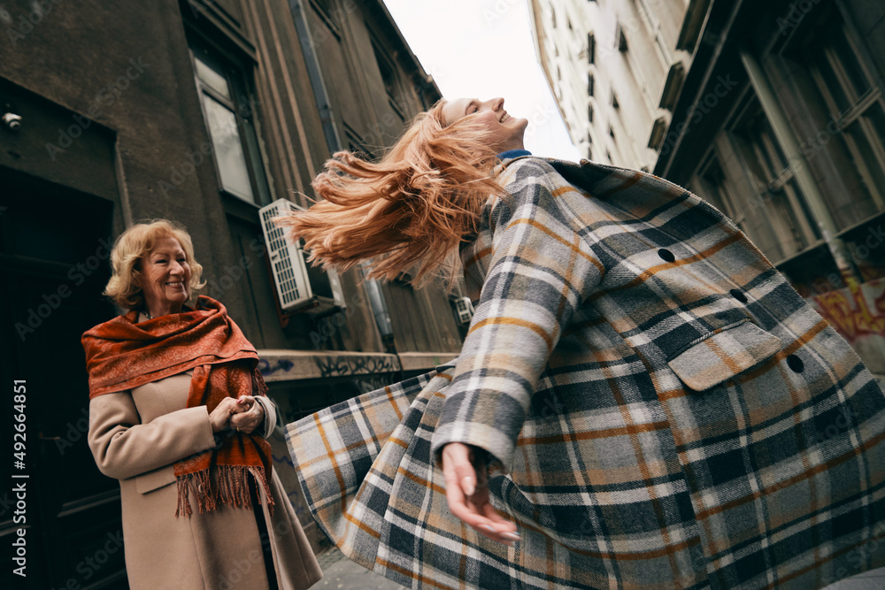 Obraz premium A playful granddaughter spins and dances for her grandmother on the street.