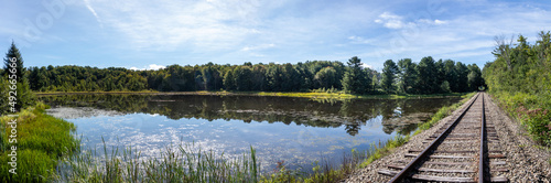 Rural New York countryside scenery showing old abandoned train tracks next to a pond in the woods