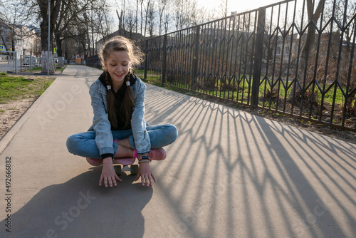 cute girl in jeans and pink sneakers rides a penny skate longboard around the city. International Skateboarding Day. Sports and Development Concept