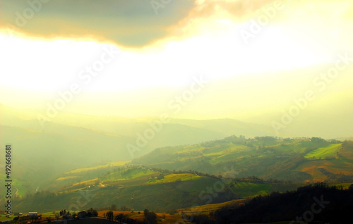 View from top on a hilly landscape illuminated by sunshine coming out of a heavy cloud in Penna San Giovanni