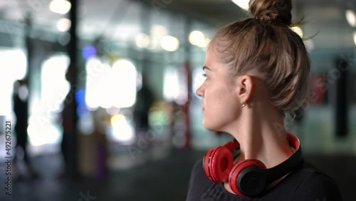 Close-up portrait of hesitating Caucasian young woman standing in gym looking around with dissatisfied facial expression. Unsure attractive newbie in sports club indoors posing shaking head no gesture