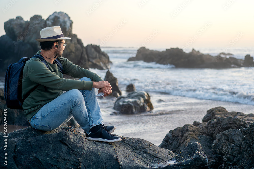 person sitting on the beach outdoors with a smartphone  watching the horizon