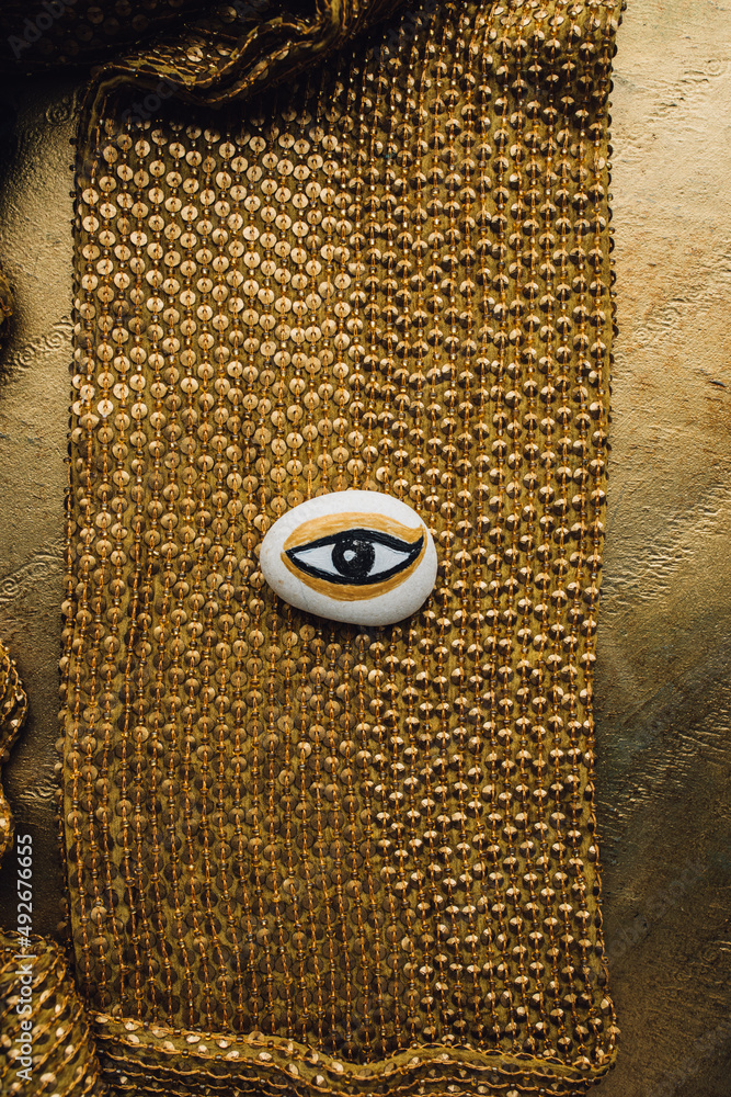 hand painted white, gold, black evil eye rock in the middle of gold ...