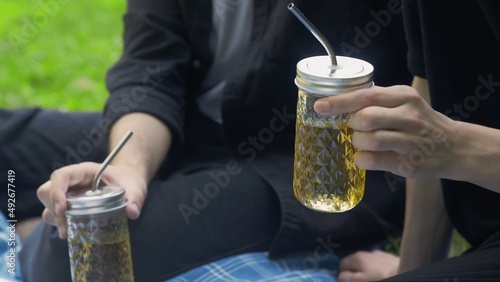 Men's hands hold a glass with a drink at a picnic in the park in summer. LGBT