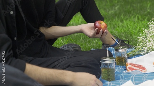 A guy gives an apple in the hand to another guy at a picnic in the summer. LGBT