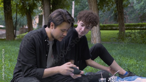 The guy plays the game on the phone, and the second watches the process in nature in the summer. LGBT