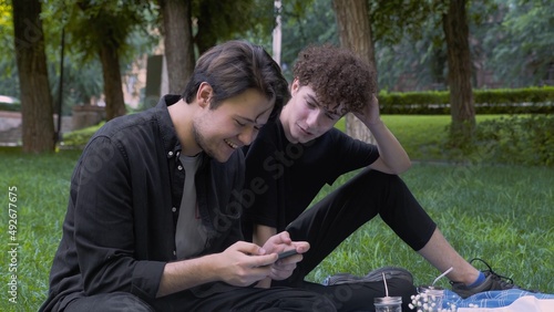 The guy plays the game on the phone, and the second watches the process in nature in the summer. LGBT