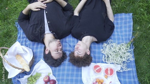 Two guys in love in the summer lie on a blanket in nature and communicate top view. LGBT