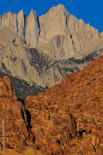Early morning light on the sheer east face of Mount Whitney, behind the rugged rock formations of the Alabama Hills National Scenic Area, Lone Pine, Eastern Sierra, California, USA