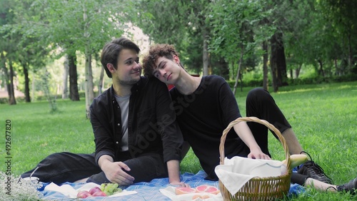 The guy slowly lowers his head on the shoulder of another guy in nature in the summer. LGBT