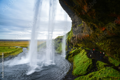Tourists walking under Seljalandsfoss waterfall  southern Iceland