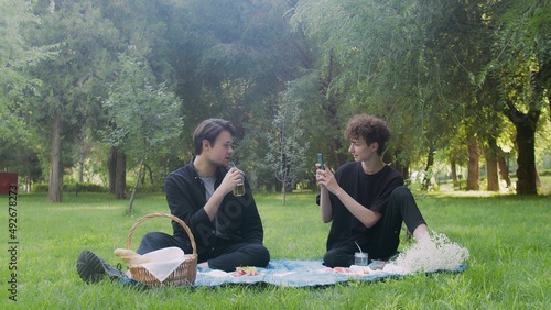 A guy takes pictures on the phone of another guy in nature in the summer. LGBT