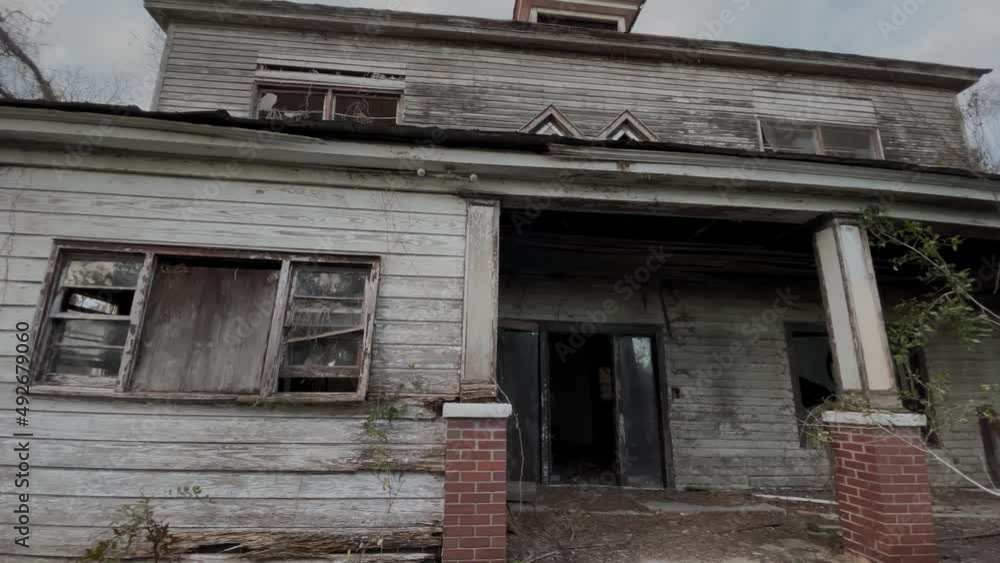 Old wooden white abandoned house with red tin roof wide front facade pan Old wooden white abandoned house with red tin roof wide front facade pan