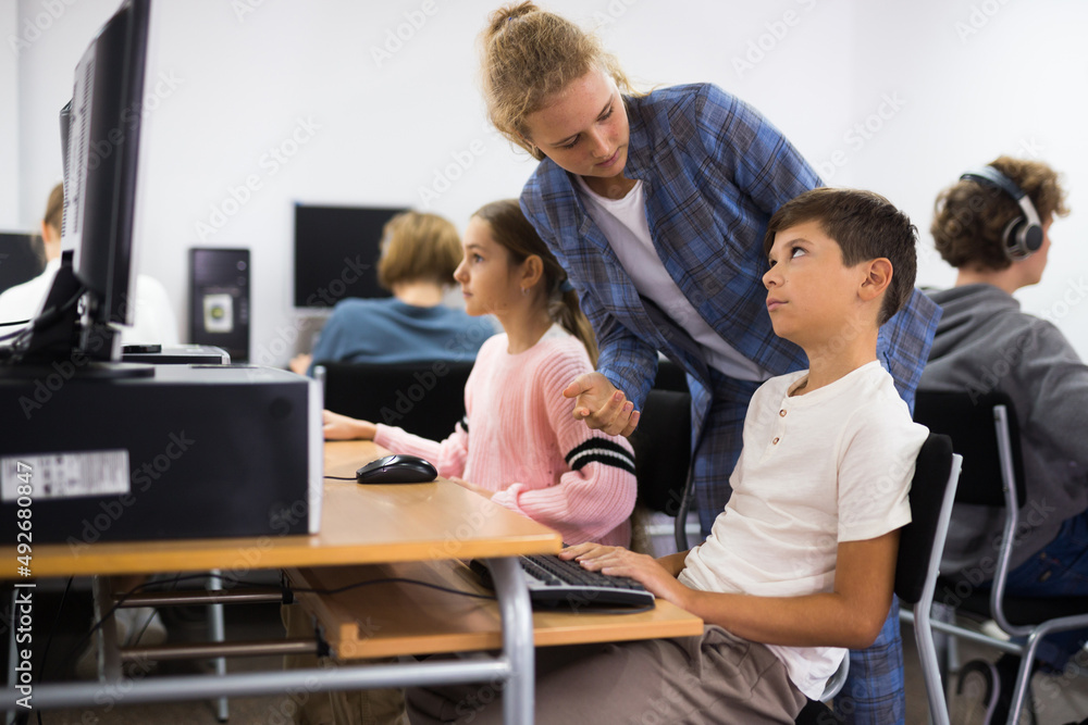 Fototapeta premium Female teacher helping student with computer work