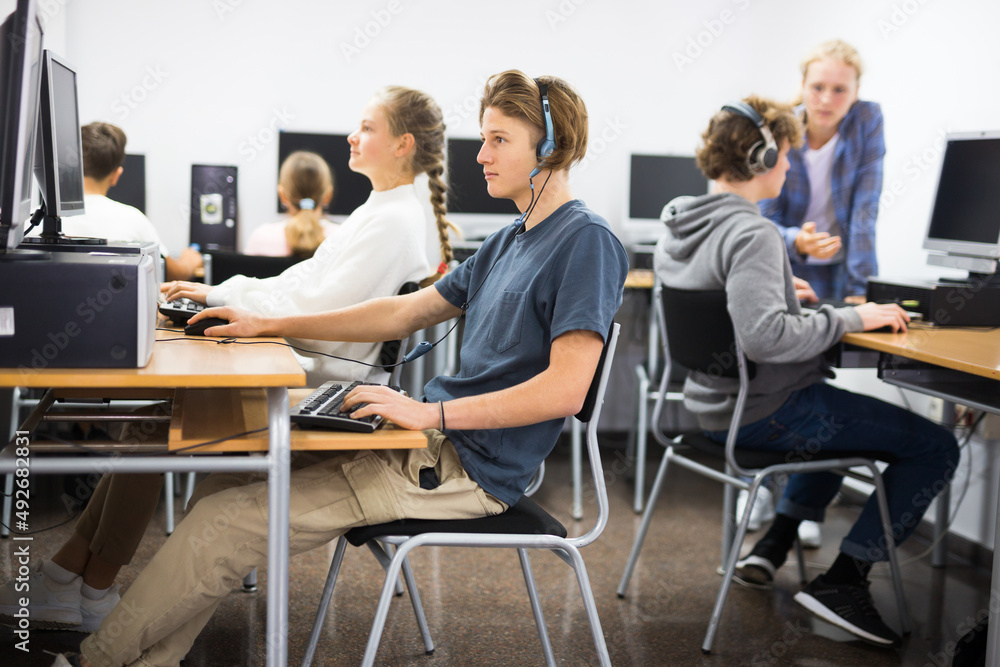Teenage student in headphones at the computer in a school class
