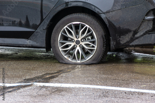 a car with a flat tire stands on asphalt wet from the rain