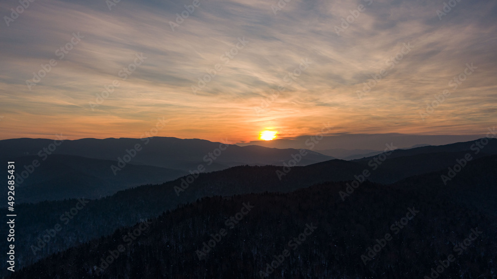 Obraz premium Aerial drone view in mountain forest. Winter landscape. Snowy Fir and Pine trees. Snowy tree branch in a view of the winter forest. Winter landscape, forest, trees covered with frost, snow.