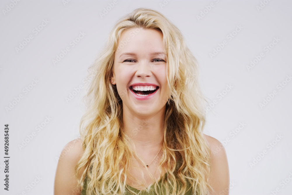 Shes amused. Studio portrait of an attractive young woman laughing while standing against a grey background. Shes amused. Studio portrait of an attractive young woman laughing while standing against a grey background.