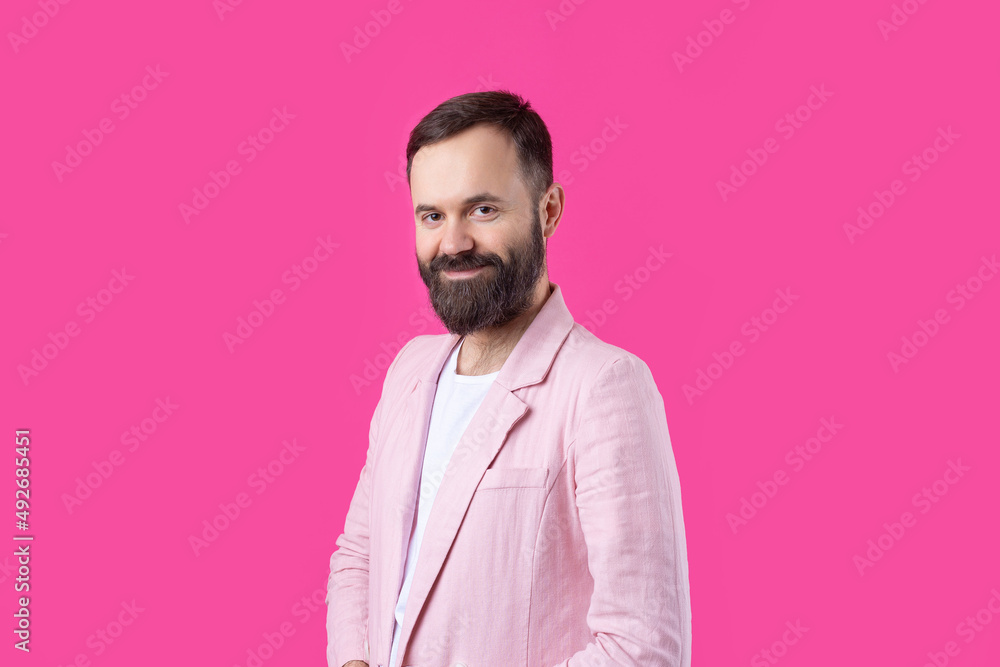Handsome man with a beard in a pink jacket is thinking over an isolated red background. Handsome man with a beard in a pink jacket is thinking over an isolated red background.