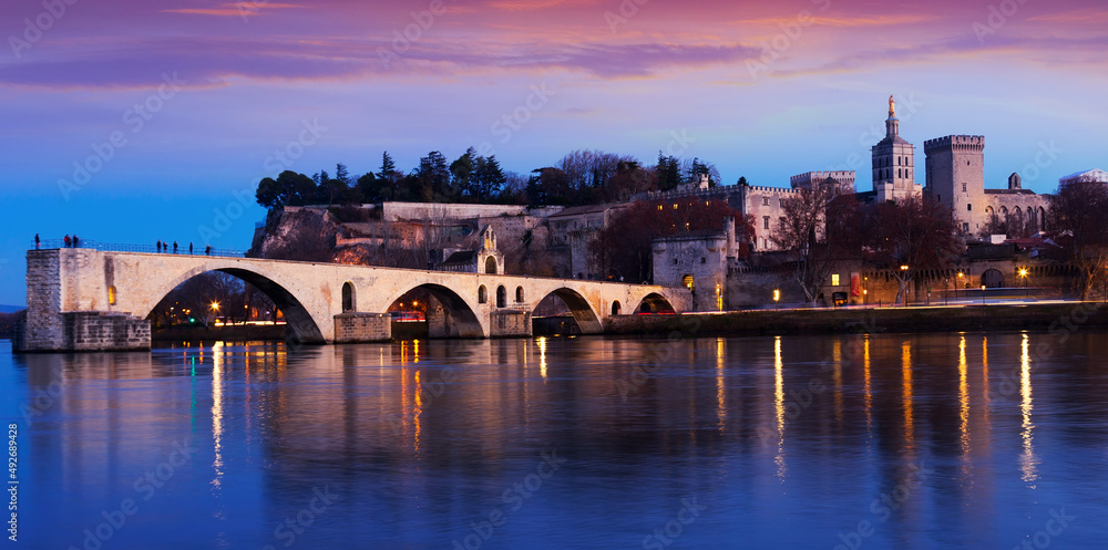 View of four surviving arches of Pont St-Benezet and Avignon Cathedral at sunset, France