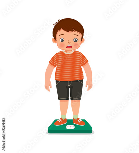 overweight little boy with body fat standing on the weighing scale look surprise when measuring his weight 