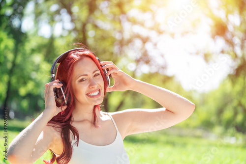 Young woman happens to have music in a summer park