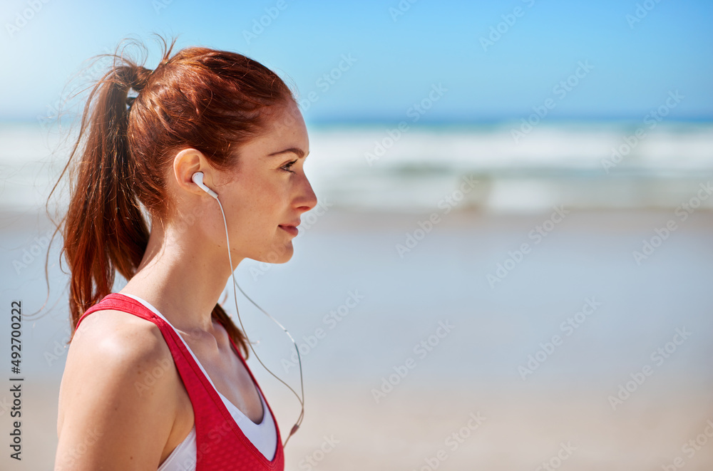 Its the music that motivates her. Cropped shot of a sporty young woman on the beach. Its the music that motivates her. Cropped shot of a sporty young woman on the beach.