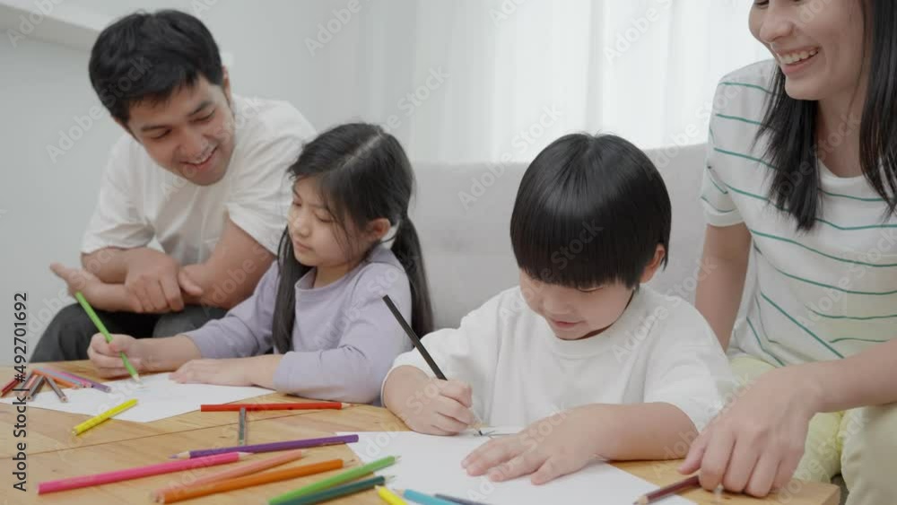 Asian family smiling laughing and having fun inside the house. Father and mother teach lovely son and daughter to draw and paint. Relaxing vacation and family happiness together. Holiday activities. Asian family smiling laughing and having fun inside the house. Father and mother teach lovely son and daughter to draw and paint. Relaxing vacation and family happiness together. Holiday activities.