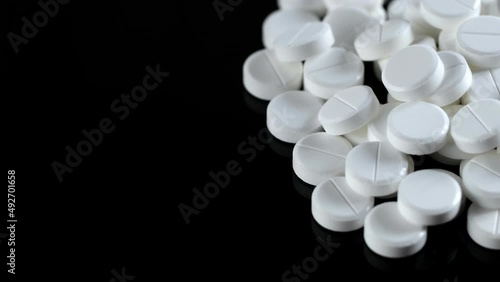 Many white round pills. Pharmaceutical production. Drugs on the production line. Moving background. close-up. view from above. white medical pills rotating closeup. Pills and drugs. Pharmaceutical photo