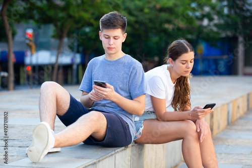 Teenagers are playing on smartphone on city street