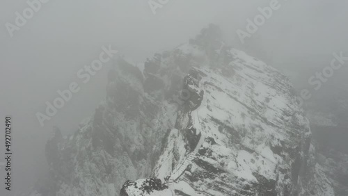 Drone shot aboce the ridge of Ninho da Manta in Madeira during a snowstorm with a moody, dark and suspense feeling. photo