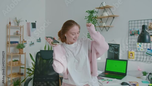 Happy woman designer dancing while listening to music