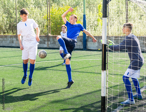 Youthful football players challenging for ball in goalmouth zone