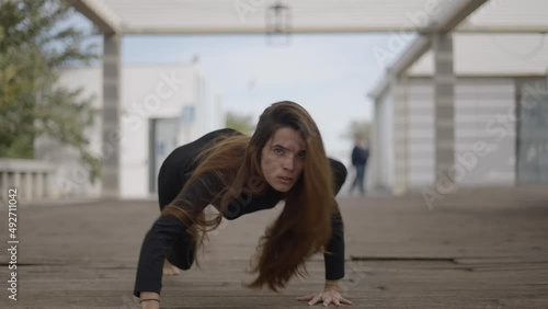 Young dark-haired woman outdoors looks crazy and crawls toward camera photo