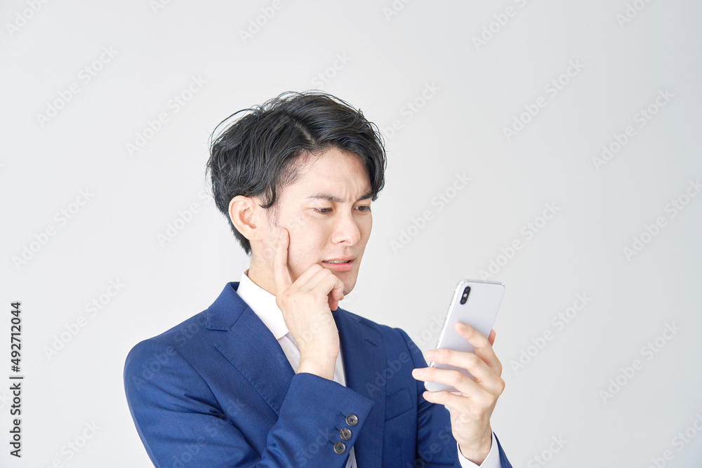 ビジネスマン　スマホ　考える　白背景