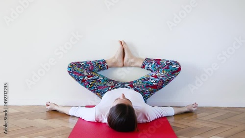 Caucasian young woman on baddhakoṇāsana, inverted butterfly yoga pose in interior room