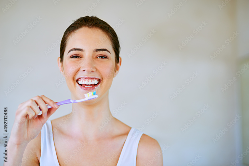 I brush because I love my teeth. Cropped shot of a young woman brushing her teeth in the bathroom. I brush because I love my teeth. Cropped shot of a young woman brushing her teeth in the bathroom.