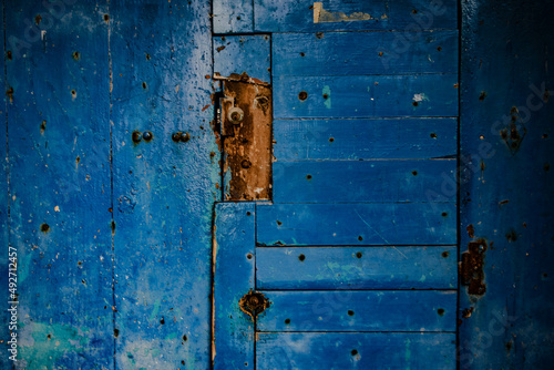 Old broken wooden door with small holes in it. Blue color vintage door.