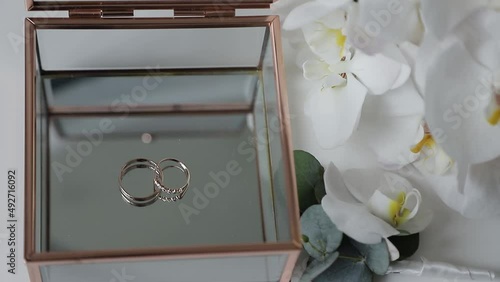 rings of the newlyweds in a transparent box, the bride's bouquet and the groom's boutonniere