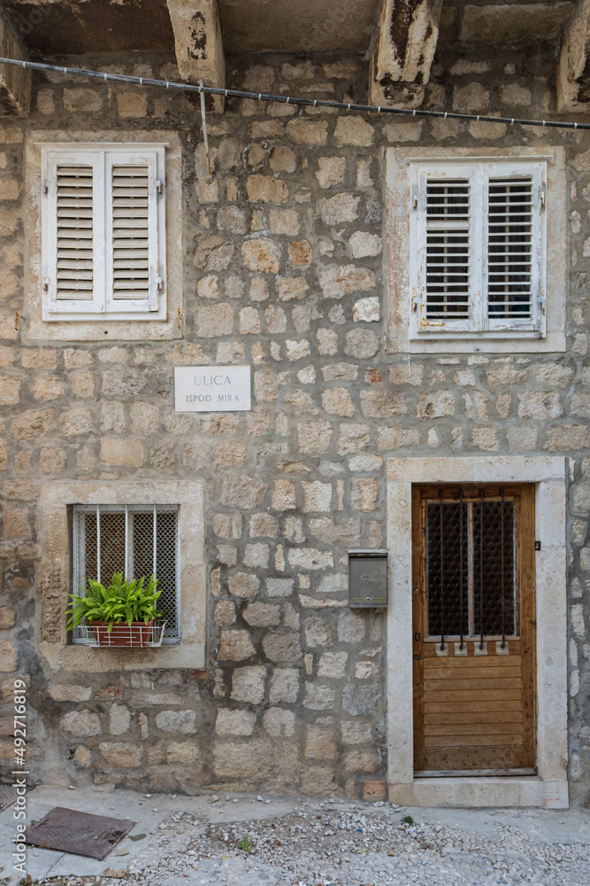 Old, weathered wooden door, windows and stone wall at the Old Town in Dubrovnik, Croatia.