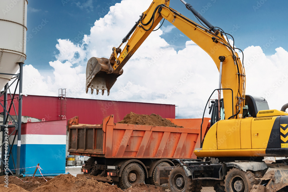 An excavator loads soil or sand into a dump truck. Pit development. Earthworks with the help of heavy construction equipment. An excavator loads soil or sand into a dump truck. Pit development. Earthworks with the help of heavy construction equipment.