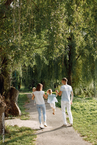 Back view photo of a family walking in a park on summer